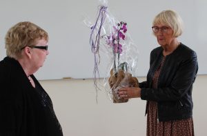 Monica lämnar över en blomma till Ingela