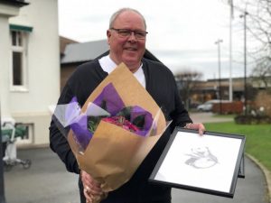 man håller blombukett och tavla