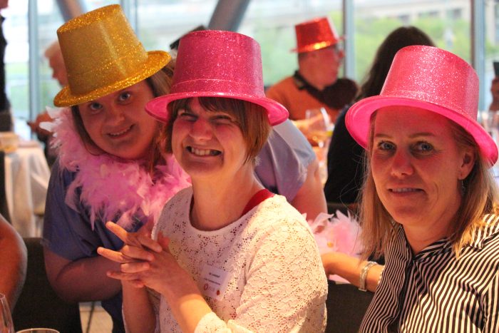 Glada deltagare som kollar på Eurovision med festliga hattar och fjädrar!