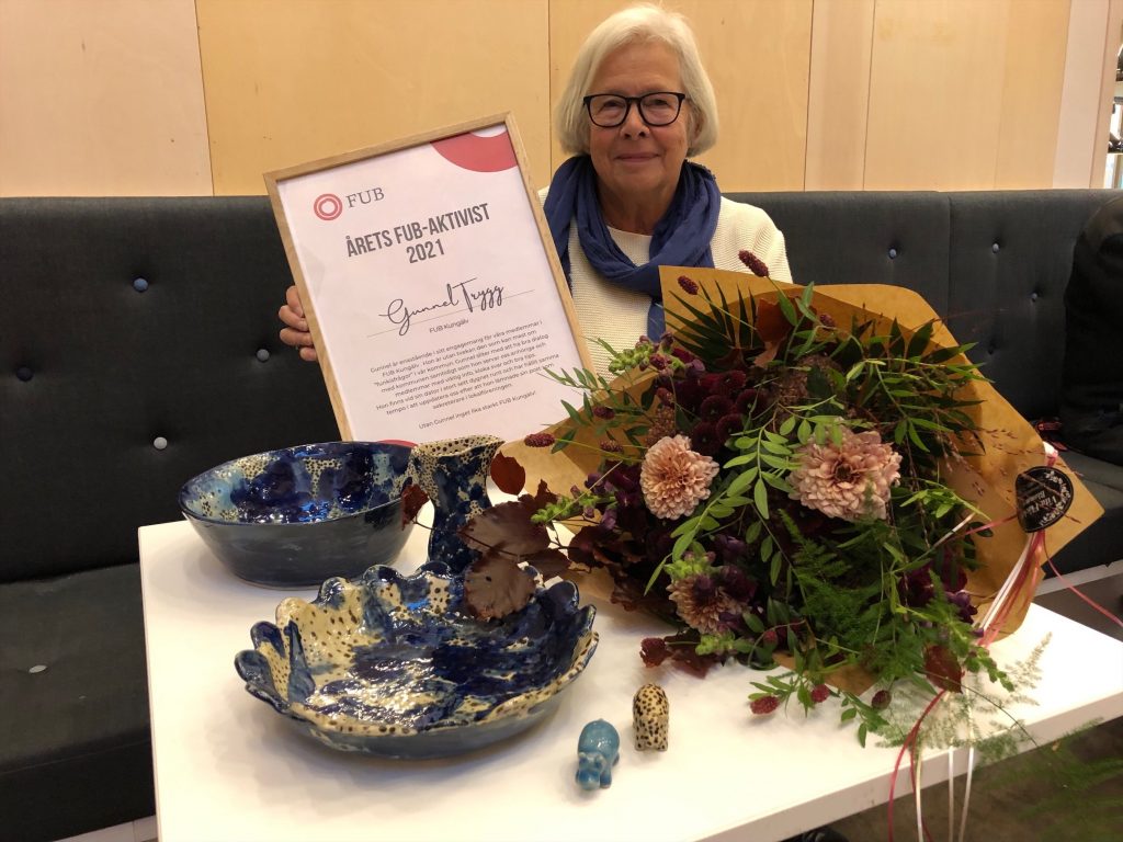Gunnel Trygg med diplom, blommor och konstkeramik.