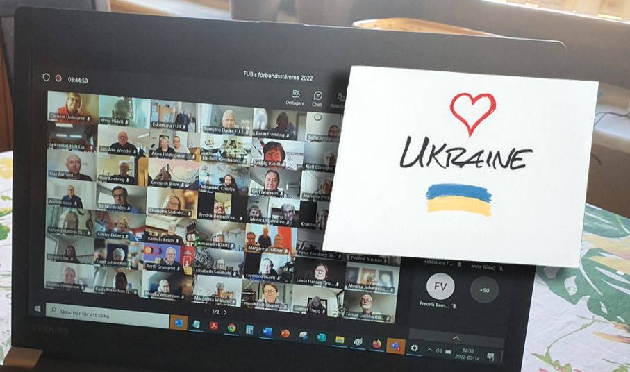 FUB:s förbundsstämma på datorskärmen, papper med hjärta texten Ukraine och Ukrainas flagga ritad.