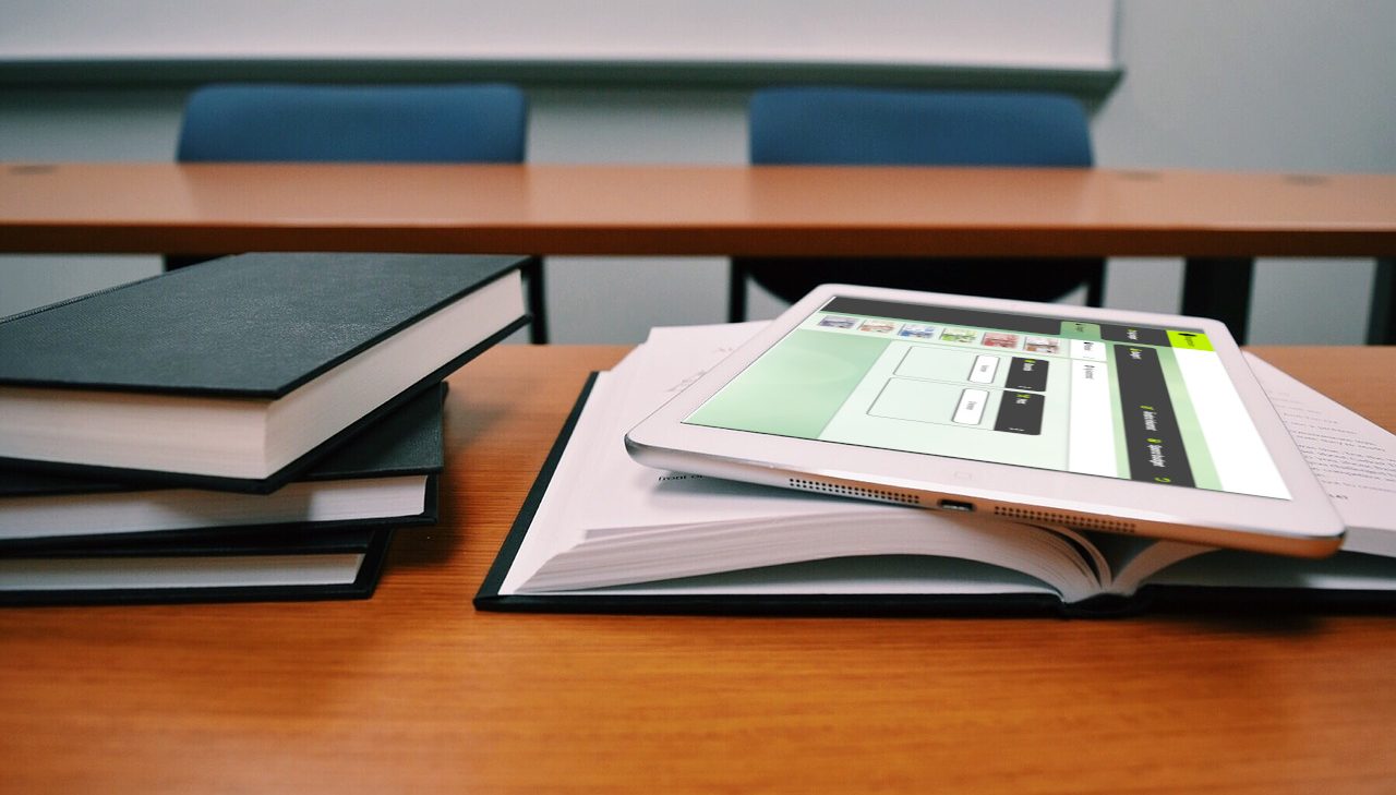 Böcker på ett bord och ipad med appen Budgettavlan